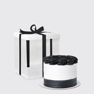 White gift box with black ribbon next to floral arrangement in chic black and white pot