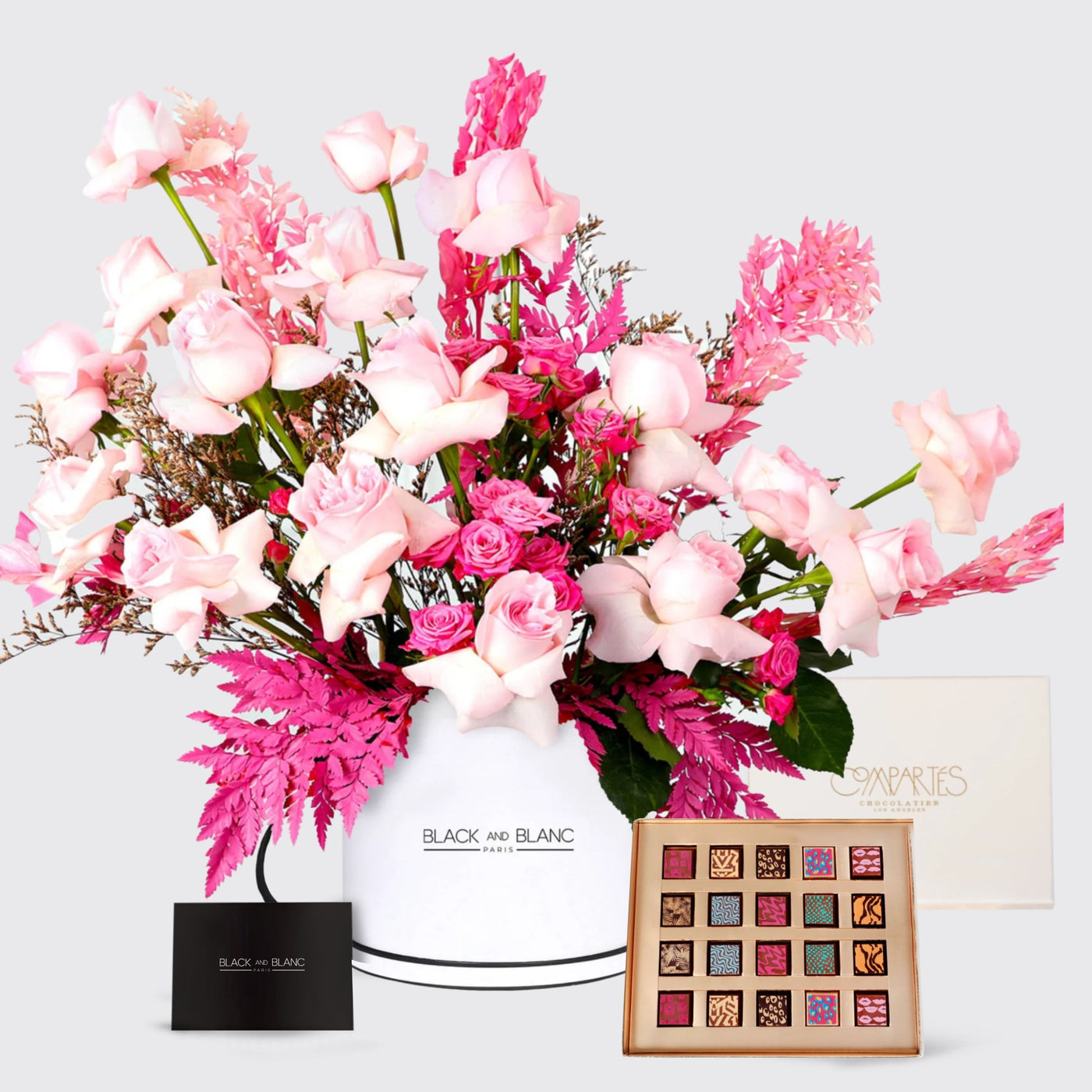 Vibrant pink flowers in a white vase with Compartes Rosé Delight chocolates