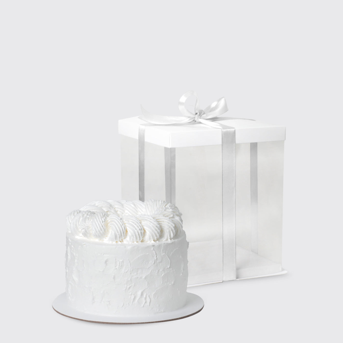 White frosted cake with swirled icing beside a gift box for Dior Eternal Elegance Set