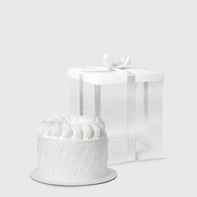 White frosted cake with swirled icing beside a gift box for Dior Eternal Elegance Set