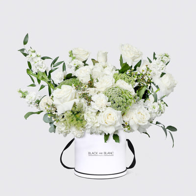 White floral arrangement in a round box labeled Black and Blanc for Jardin Blanc