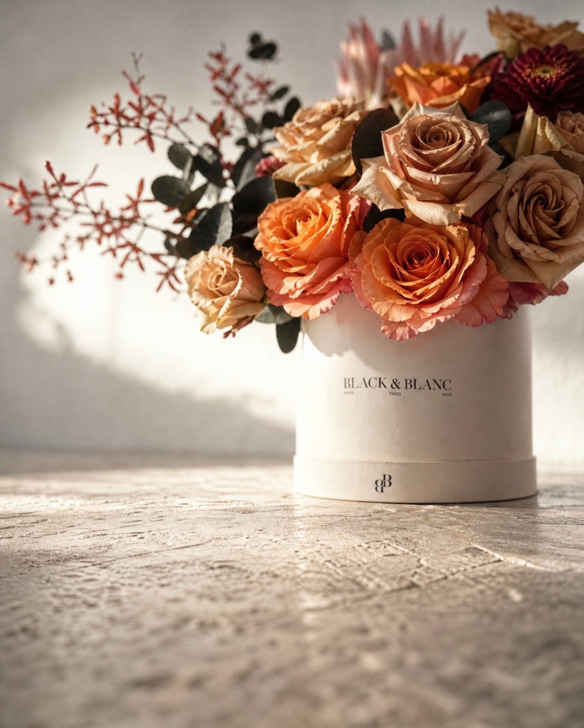Toffee, amber and copper roses with oxblood chrysanthemum in a Black & Blanc box, in raking late sun