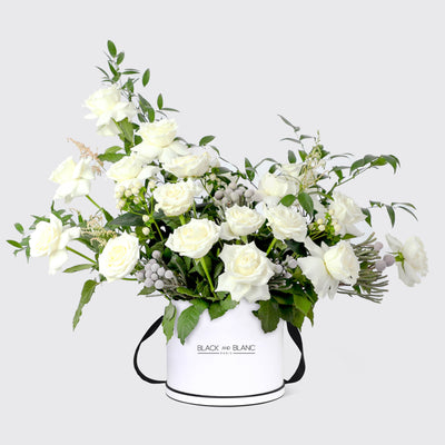 Elegant white rose floral arrangement in a chic cylindrical container