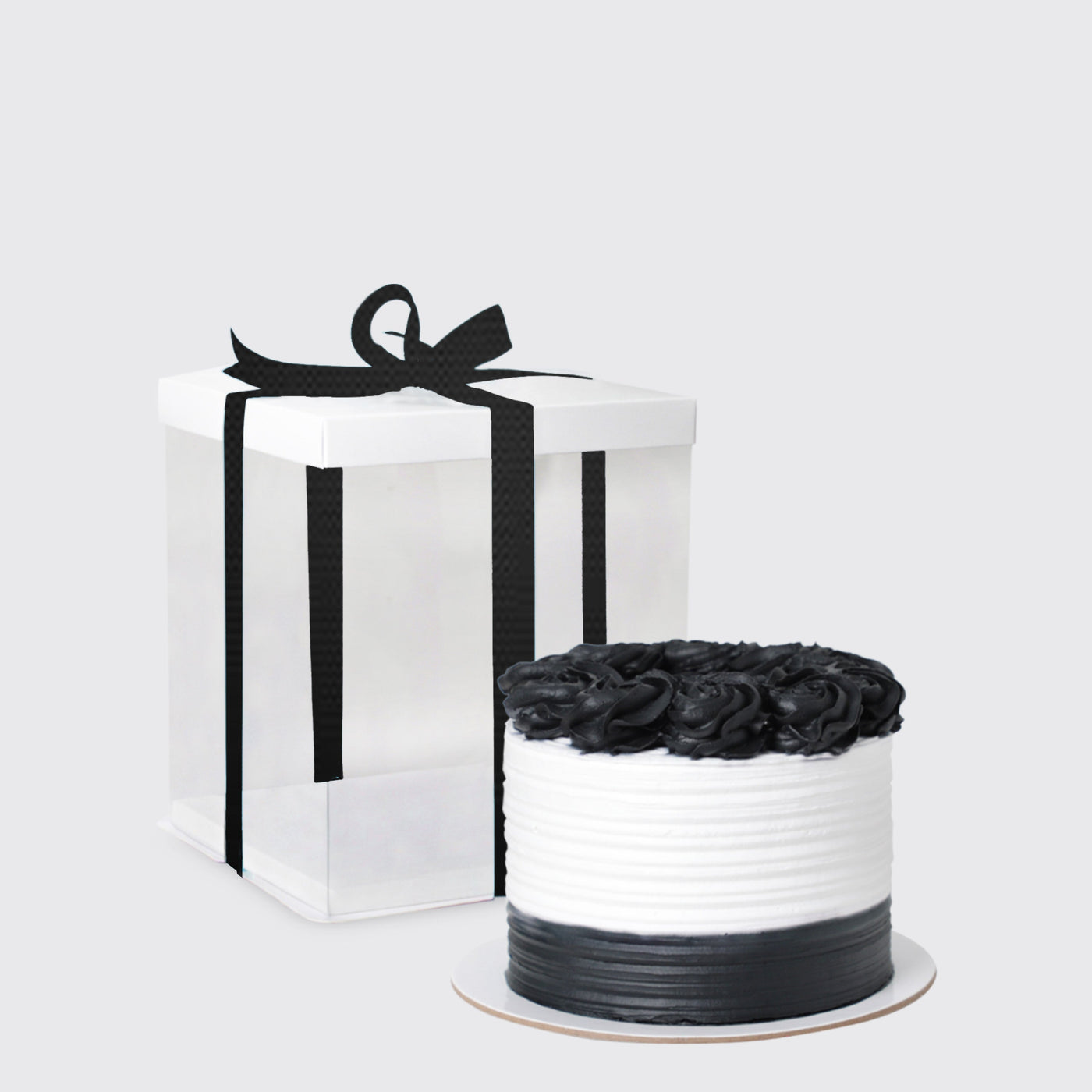 White gift box with black ribbon next to round floral arrangement in chic container