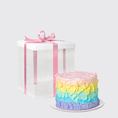 Colorful pastel rainbow cake with textured frosting and white gift box with pink ribbon