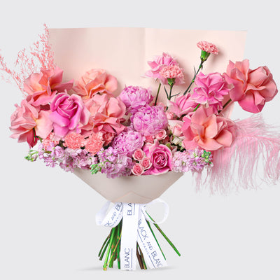 Vibrant Pink Paradise Bouqs featuring pink and coral flowers with a white ribbon