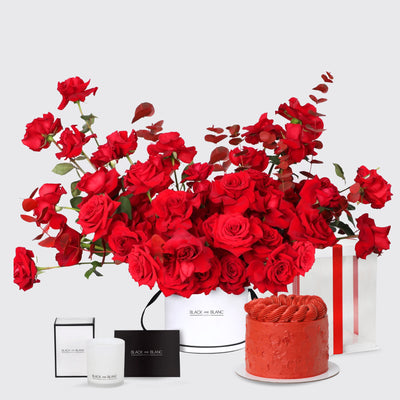 Vibrant red roses in a white container with a red cake and gift boxes in Scarlet Splendor Set