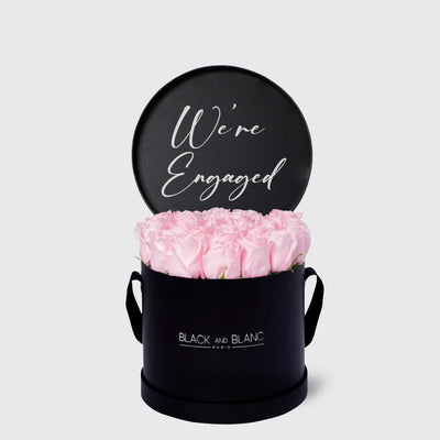 Black cylindrical box with pink roses and a We’re Engaged sign from Texte De Fleur