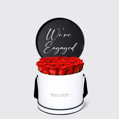 Cylindrical white box with red roses and black We’re Engaged sign from Texte De Fleur