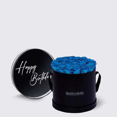 Circular black box of Infinity Roses with vibrant blue blooms and Happy Birthday lid