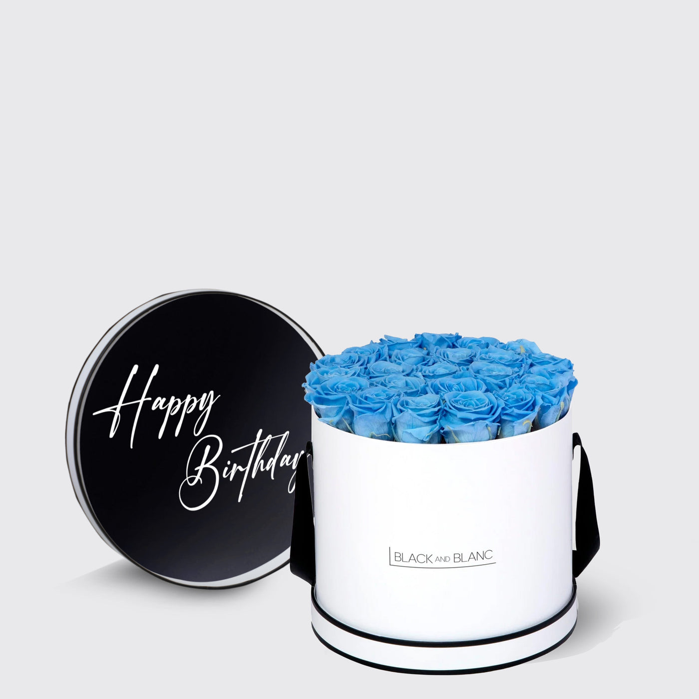 Cylindrical white box of infinity roses in blue, black lid says Happy Birthday