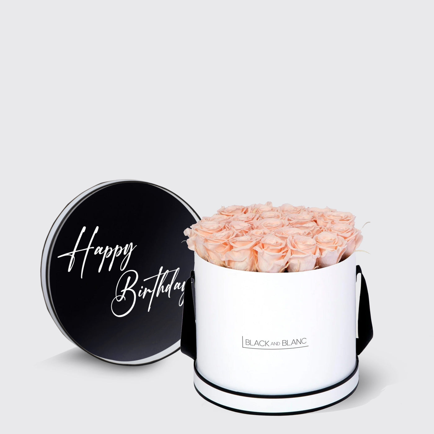 Cylindrical white box of pink infinity roses with black lid saying Happy Birthday