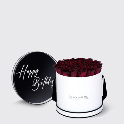 Cylindrical white box of infinity roses with a black lid saying Happy Birthday