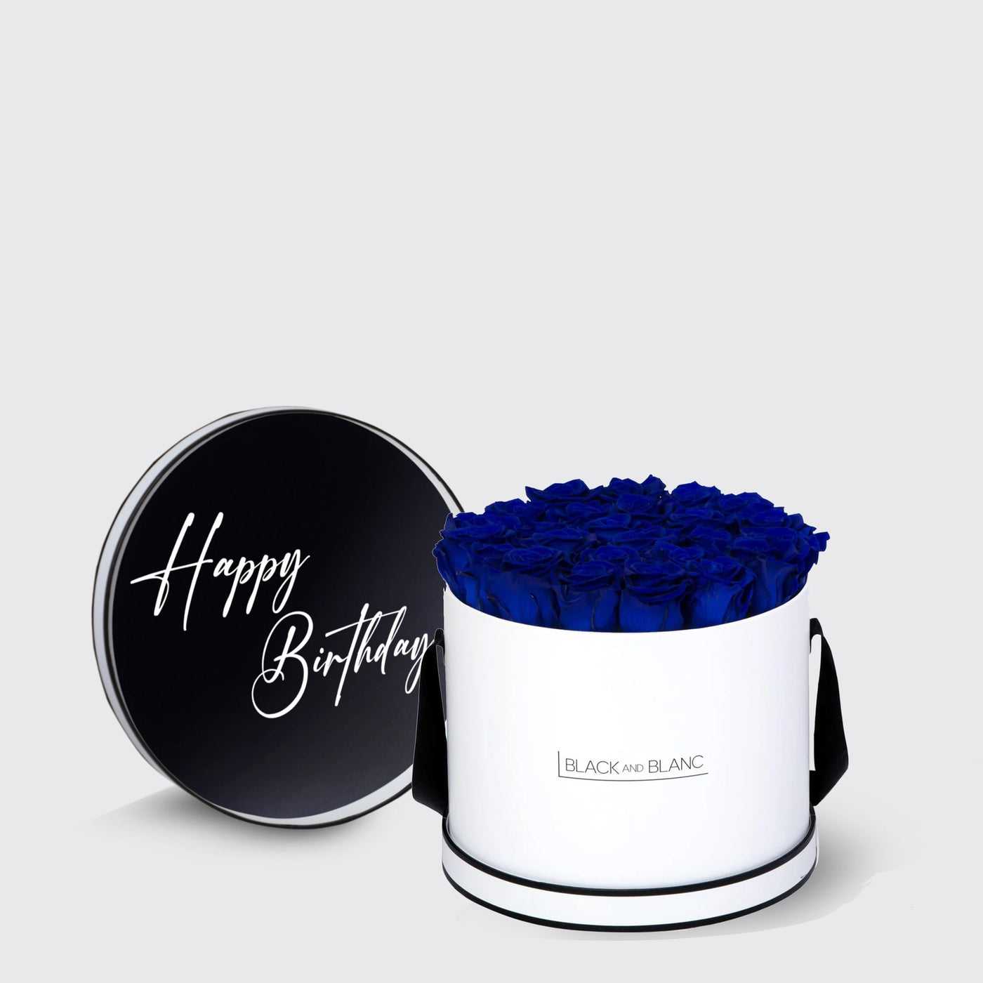 Cylindrical white box of blue infinity roses with black lid saying Happy Birthday