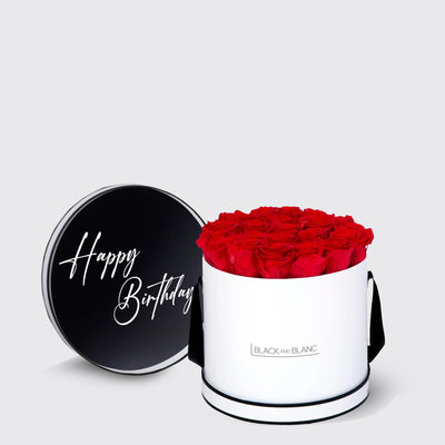 Cylindrical white box filled with red infinity roses and a black Happy Birthday lid