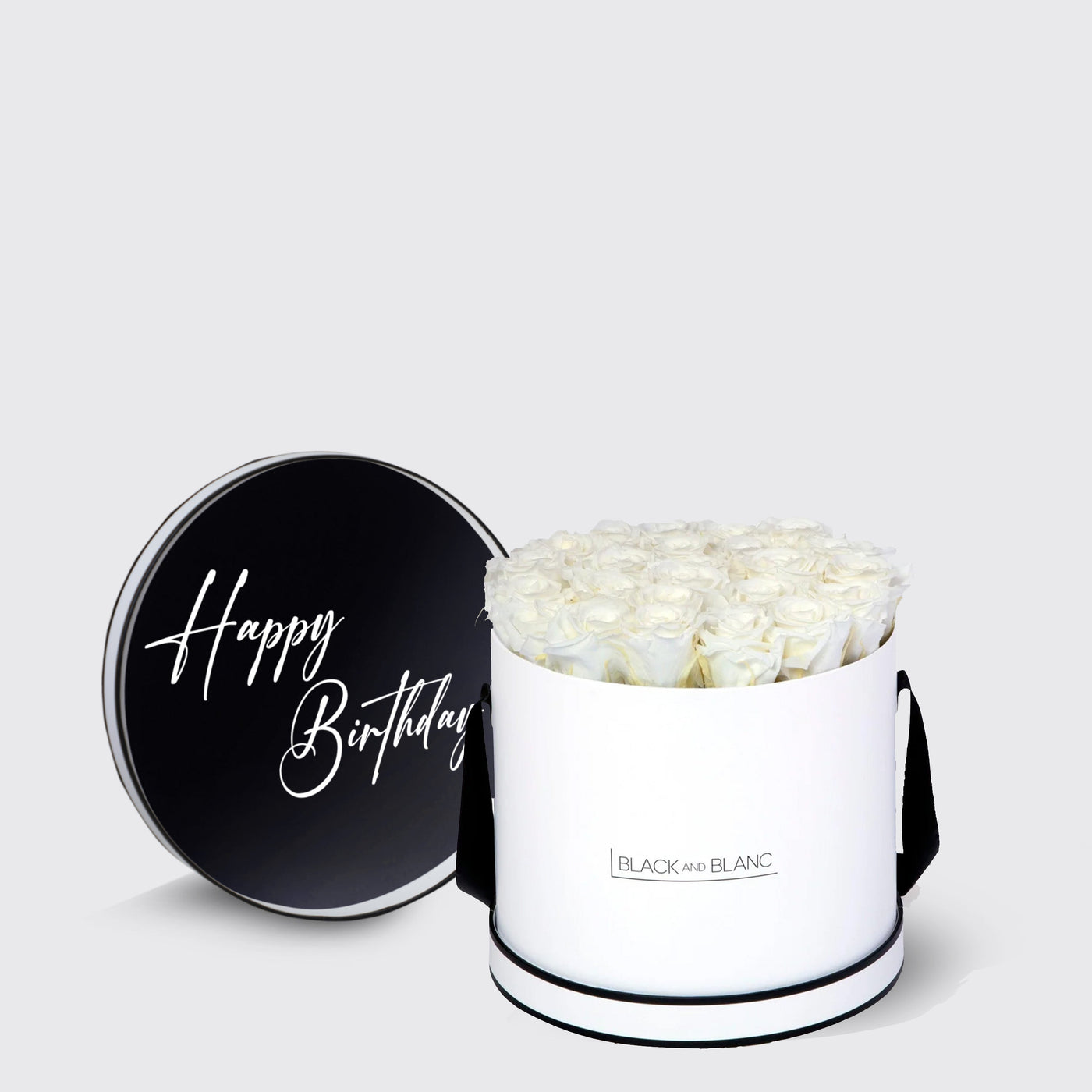 Circular white box of infinity roses with black lid saying Happy Birthday