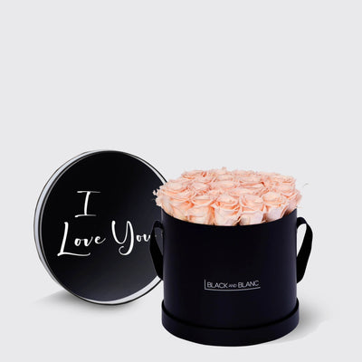 Elegant black round box of infinity roses in pale pink, lid reads I Love You