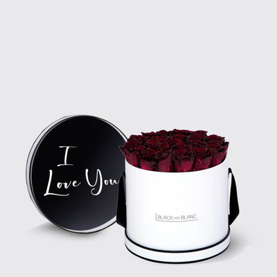 Cylindrical white box of infinity roses with a black lid saying I Love You in white script