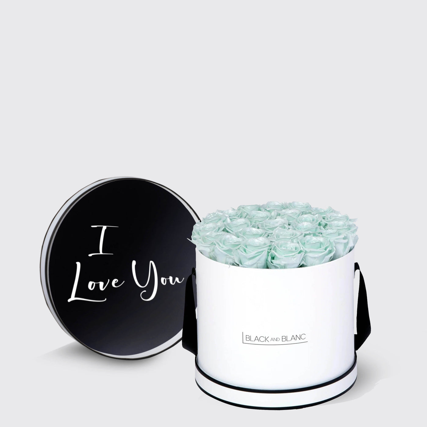 Cylindrical white box with pale green infinity roses and black lid saying I Love You