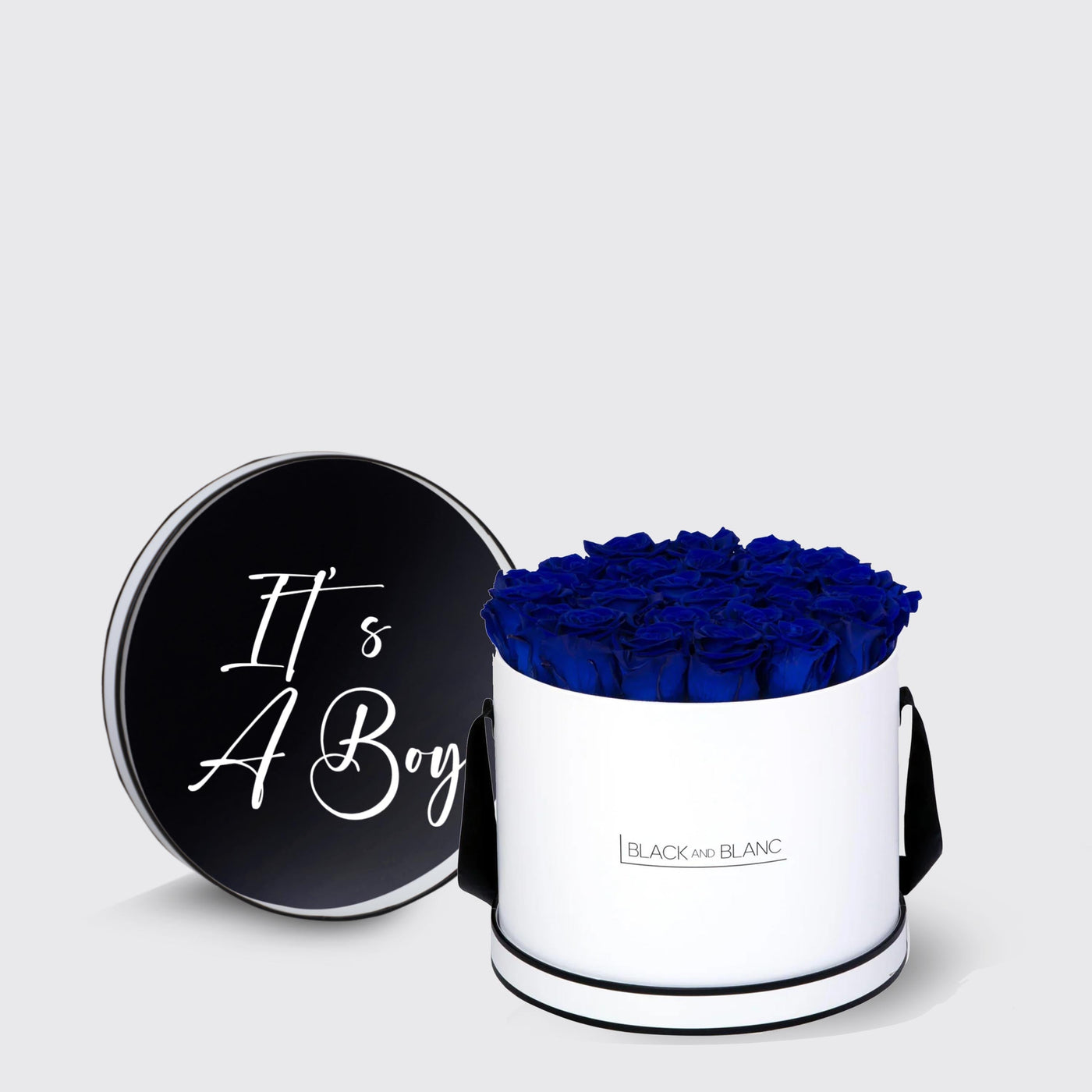 Cylindrical white box of blue infinity roses with black lid saying It’s A Boy