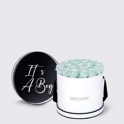 Cylindrical white box with light blue infinity roses and black lid saying Its A Boy