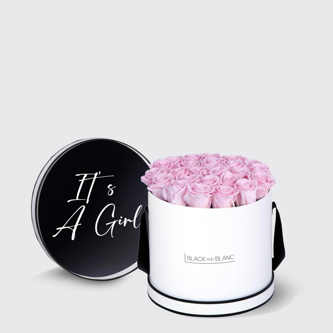 Cylindrical white box with pink roses and black lid that says It’s A Girl