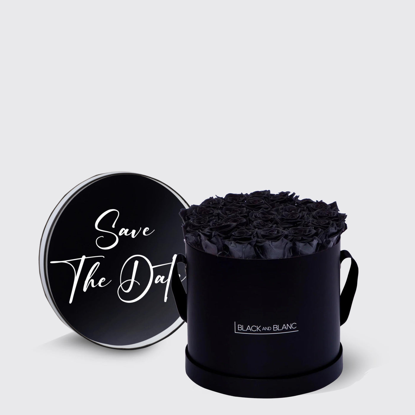 Black cylindrical box with dark roses and Save The Date lid, featuring infinity roses