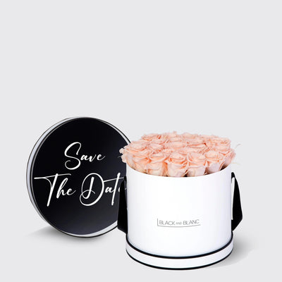 Cylindrical white box of light pink infinity roses with black lid and Save The Date design