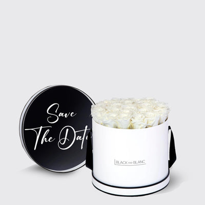 Cylindrical white box with infinity roses and black lid featuring Save The Date text