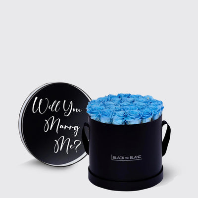 Circular black box with blue infinity roses and lid asking Will You Marry Me