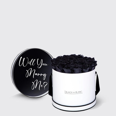 Cylindrical white box with infinity roses and black lid saying Will You Marry Me