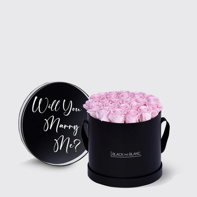 Black cylindrical box of infinity roses with lid asking Will You Marry Me