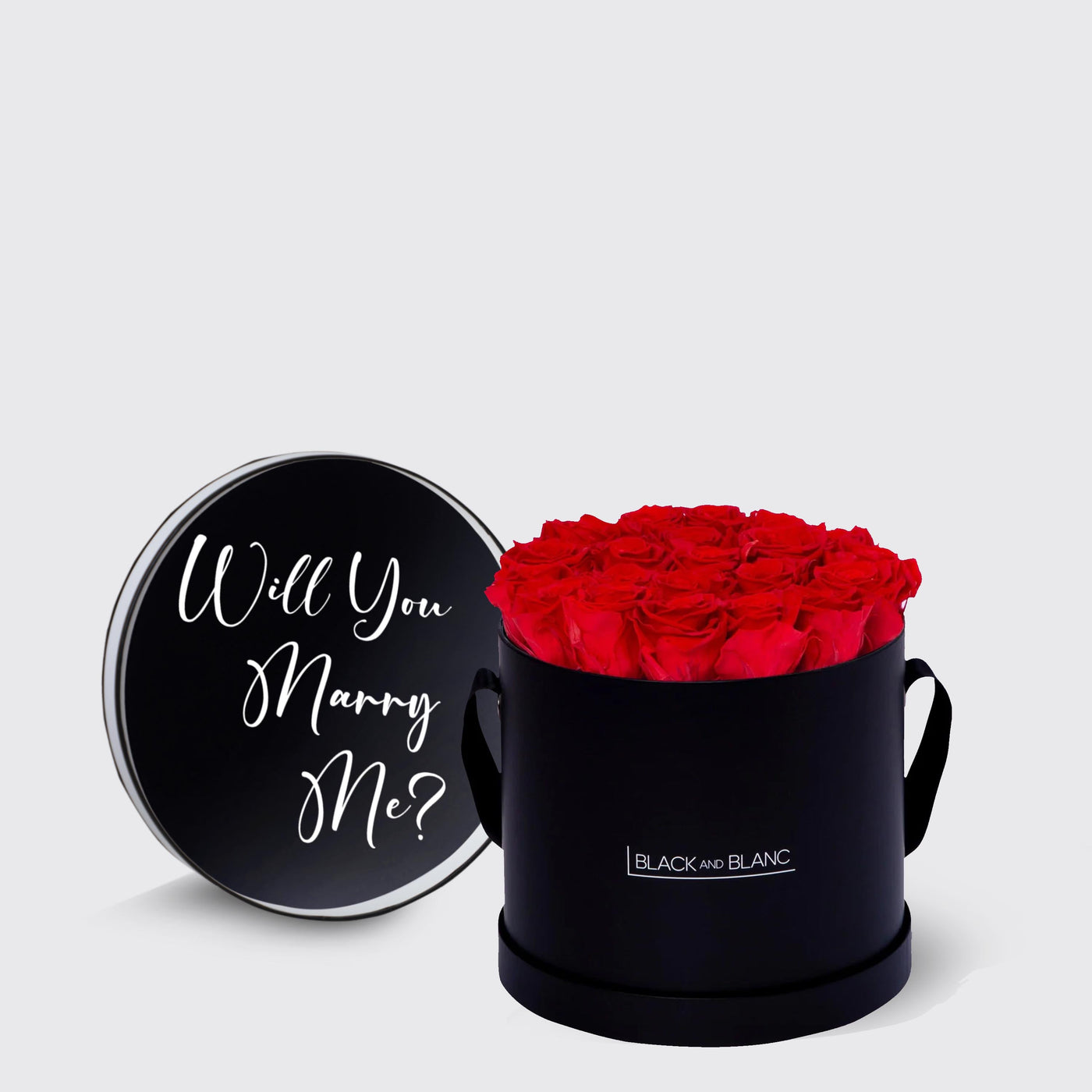 Black cylindrical box with infinity roses and a lid that asks Will You Marry Me