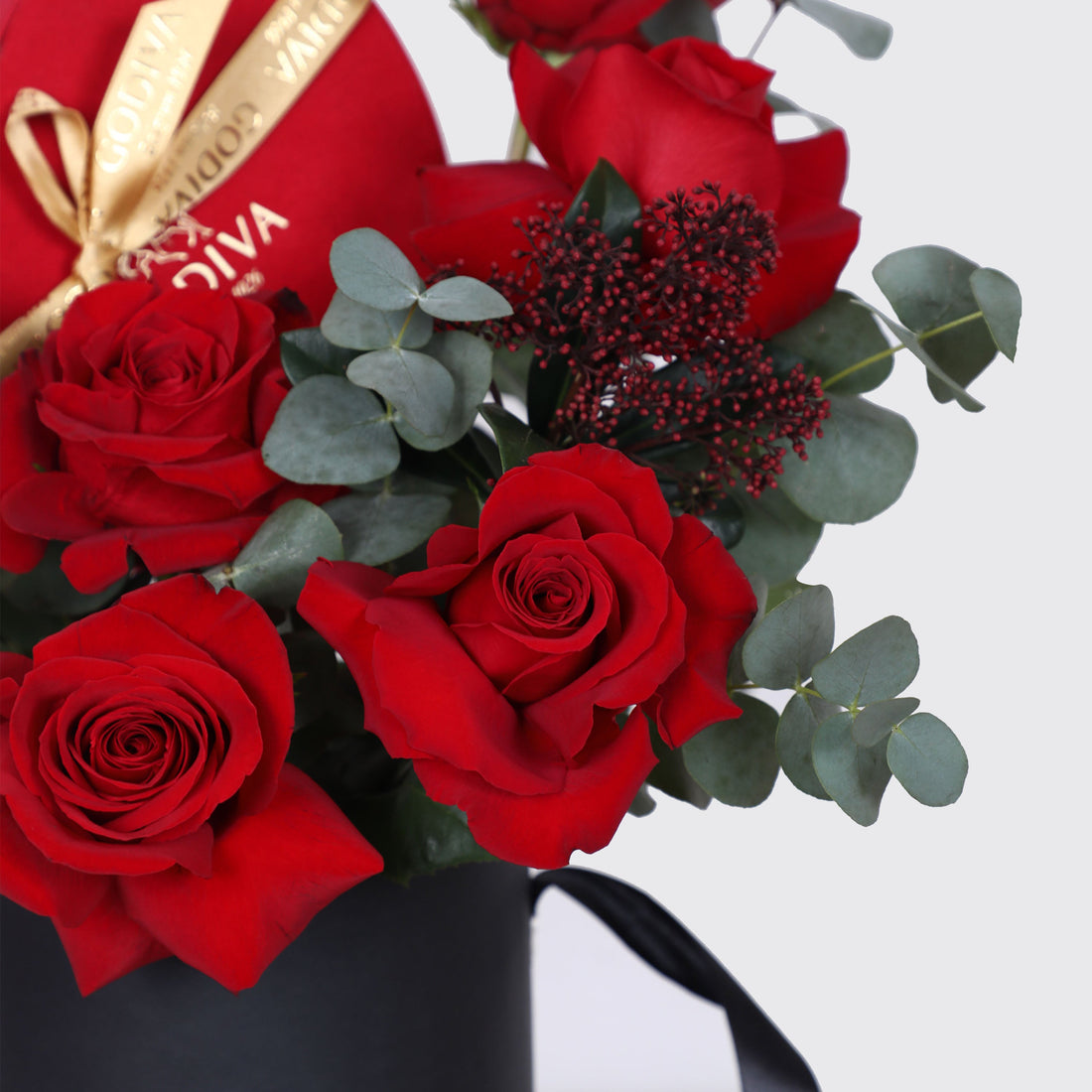 Bouquet of vibrant red roses and eucalyptus in a black container from the Velvet Heart Assortment